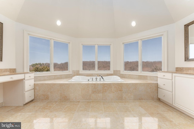 full bathroom with a wealth of natural light, vanity, a garden tub, and vaulted ceiling