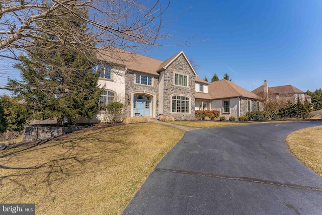 view of front of house featuring stone siding, stucco siding, and a front yard