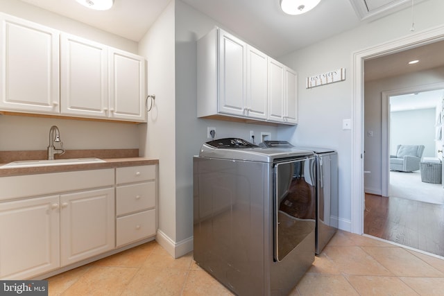 washroom with a sink, washer and dryer, cabinet space, light tile patterned floors, and baseboards