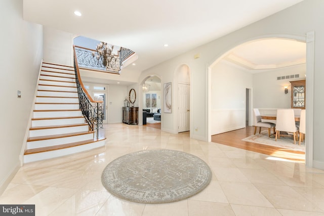 entrance foyer featuring visible vents, baseboards, stairs, recessed lighting, and arched walkways