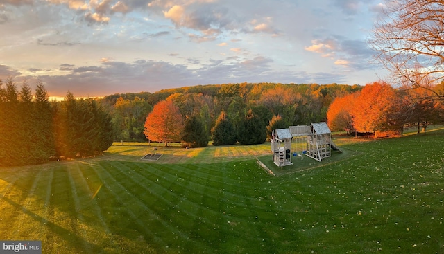 yard at dusk featuring a forest view