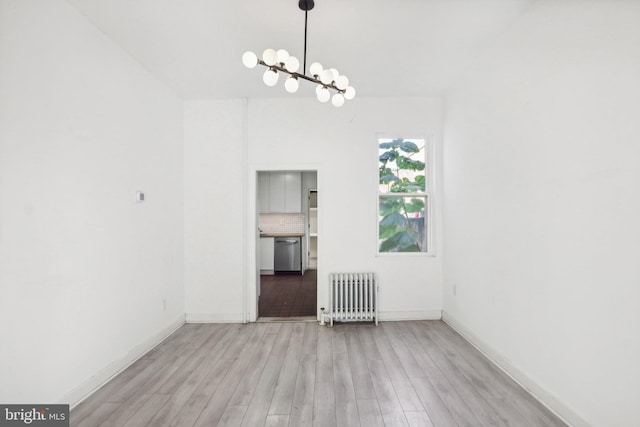 empty room with radiator heating unit, a chandelier, and light wood-type flooring