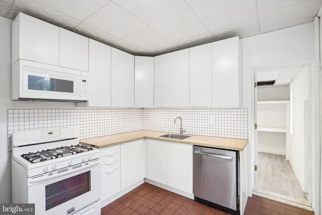 kitchen with sink, backsplash, white cabinets, and white appliances