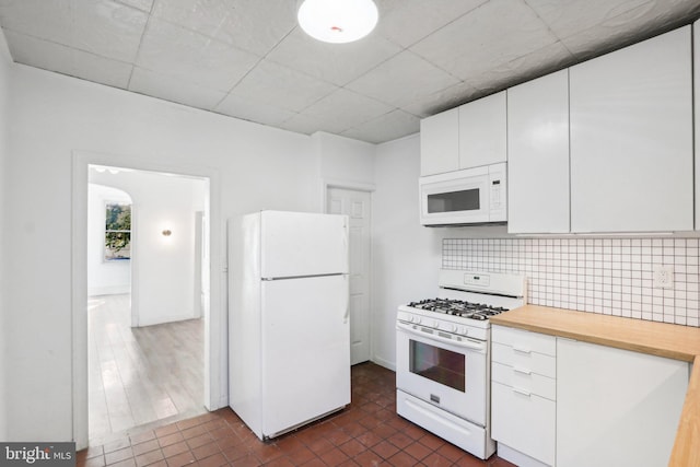 kitchen with backsplash, white appliances, and white cabinets