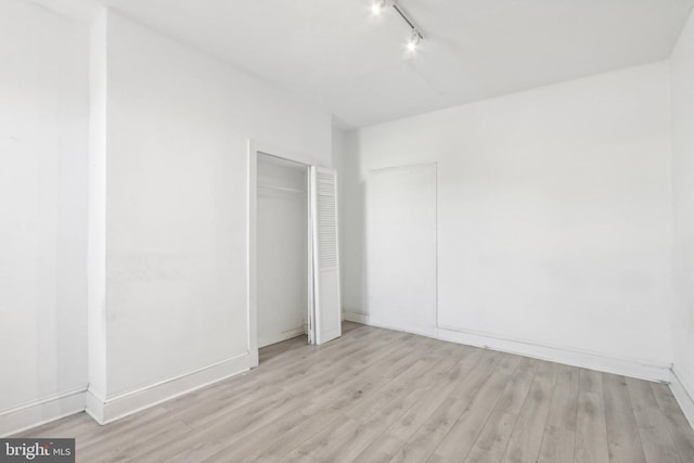 unfurnished bedroom with rail lighting and light hardwood / wood-style flooring