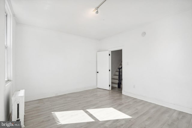 unfurnished room with radiator heating unit and light hardwood / wood-style floors