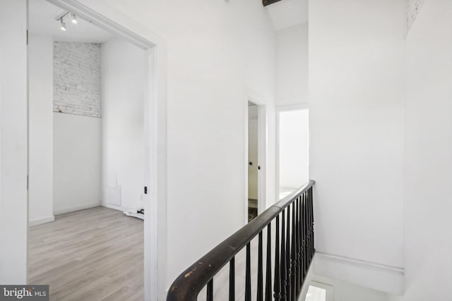 corridor with high vaulted ceiling and light wood-type flooring