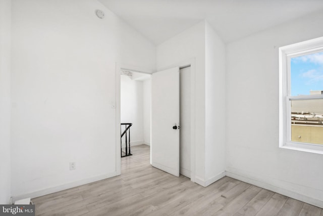 spare room featuring vaulted ceiling and light hardwood / wood-style floors