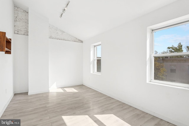 unfurnished room with lofted ceiling, track lighting, a healthy amount of sunlight, and light hardwood / wood-style flooring