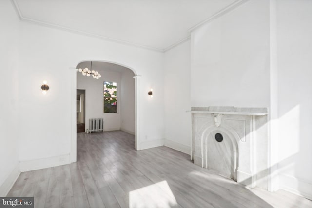 unfurnished living room with radiator, crown molding, light hardwood / wood-style flooring, and a notable chandelier