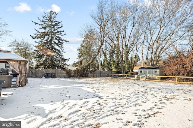 snowy yard with a gazebo and a storage unit