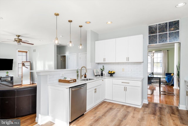 kitchen with decorative light fixtures, dishwasher, sink, and white cabinets