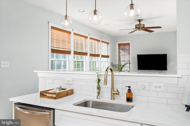 kitchen with pendant lighting, sink, dishwasher, white cabinetry, and light stone countertops