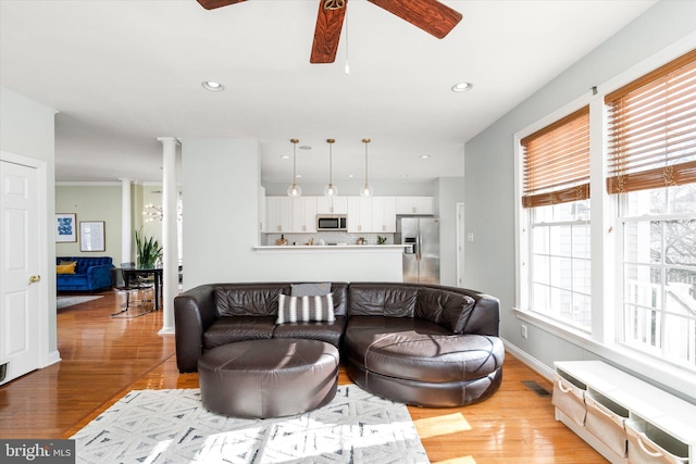 living room with ceiling fan, light hardwood / wood-style flooring, and ornate columns