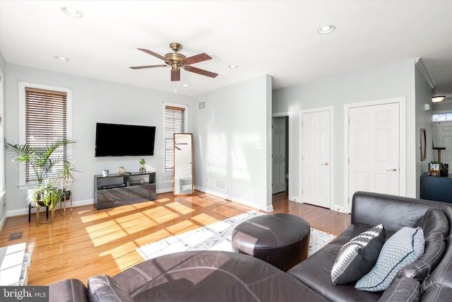 living room featuring ceiling fan, wood-type flooring, and a healthy amount of sunlight