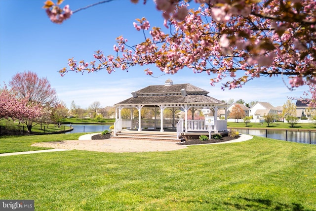 view of property's community featuring a gazebo, a water view, and a lawn