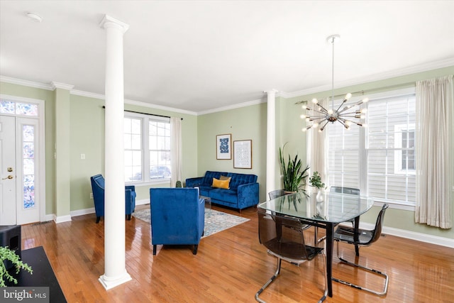 dining area with crown molding, wood-type flooring, a chandelier, and decorative columns