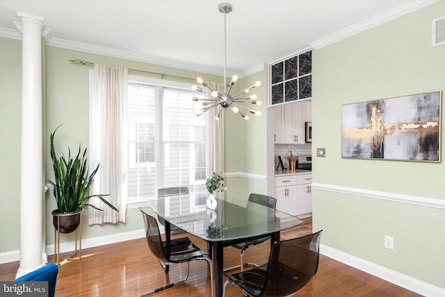 dining area with ornate columns, ornamental molding, hardwood / wood-style floors, and a chandelier