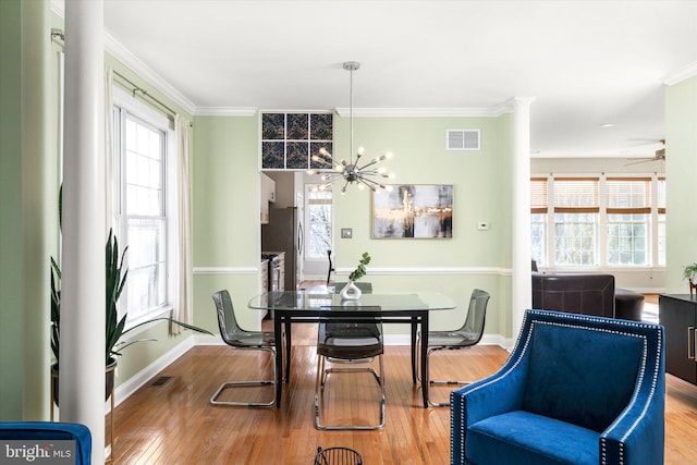 dining area with hardwood / wood-style flooring, a healthy amount of sunlight, ornamental molding, and ceiling fan with notable chandelier