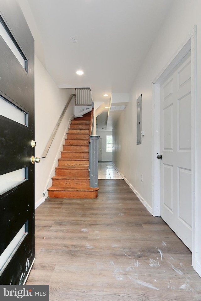 stairway with hardwood / wood-style floors and electric panel