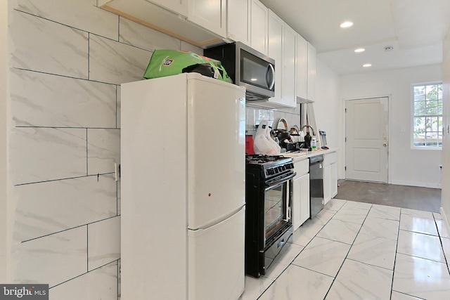 kitchen with white cabinetry, backsplash, and black appliances