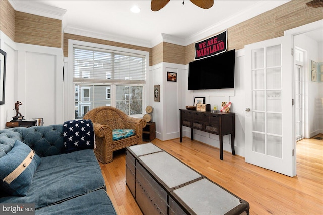 living room featuring ceiling fan, ornamental molding, and light wood-type flooring