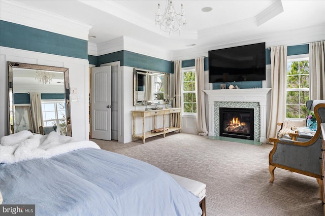 bedroom with a raised ceiling, a tile fireplace, carpet, and crown molding