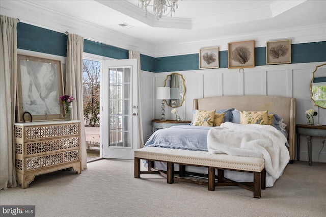 carpeted bedroom featuring a raised ceiling, ornamental molding, and a notable chandelier