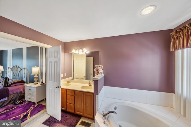 bathroom featuring tile patterned flooring, vanity, and tiled bath