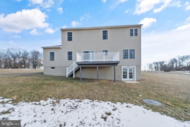 snow covered back of property with a wooden deck and a yard