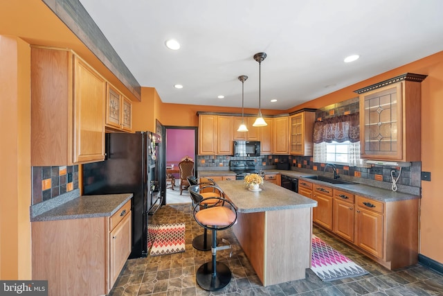 kitchen with pendant lighting, sink, a breakfast bar, black appliances, and a kitchen island