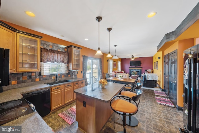 kitchen with sink, dishwasher, backsplash, a kitchen breakfast bar, and cooktop