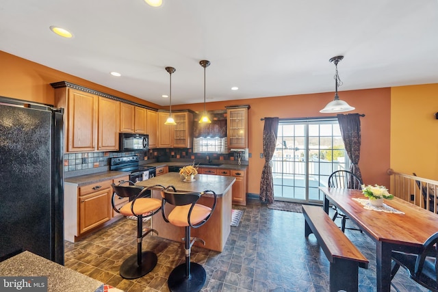 kitchen with hanging light fixtures, decorative backsplash, black appliances, and a kitchen island