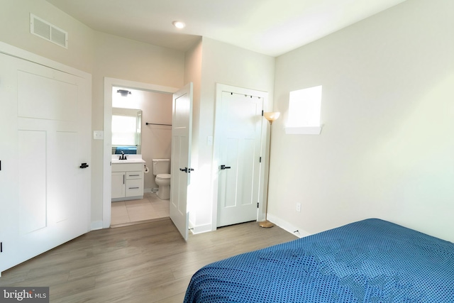 bedroom with sink, connected bathroom, and light hardwood / wood-style floors