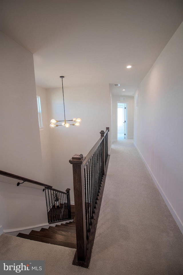 hall with carpet flooring and a notable chandelier