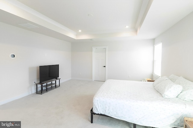 bedroom featuring a raised ceiling and light carpet