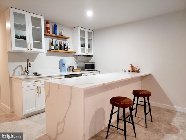 bar with white cabinetry, light carpet, sink, and light stone countertops