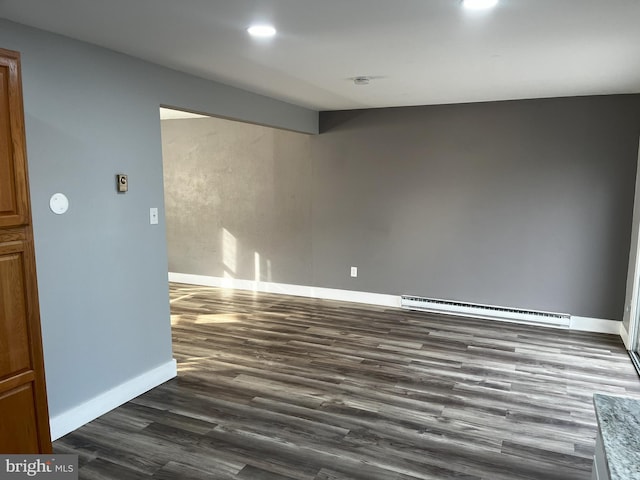 empty room with dark wood-type flooring and a baseboard radiator