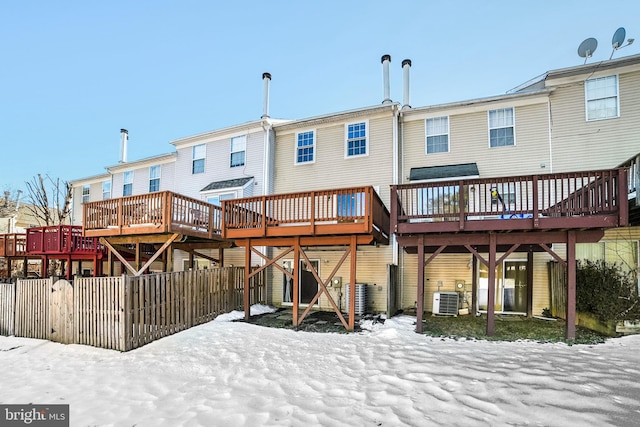 snow covered rear of property featuring a deck and central air condition unit