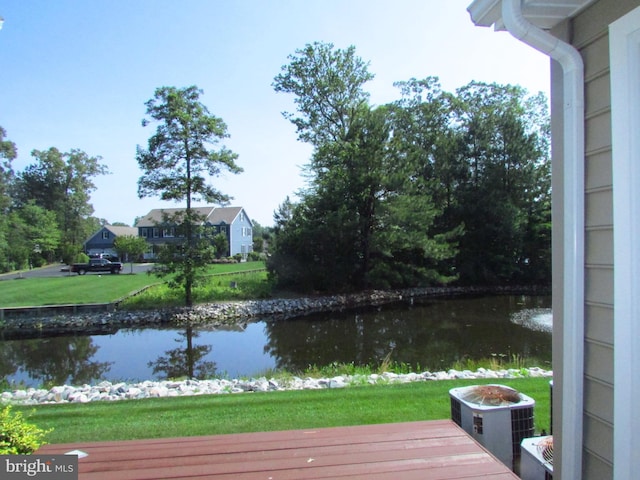 wooden terrace featuring a lawn, central air condition unit, and a water view