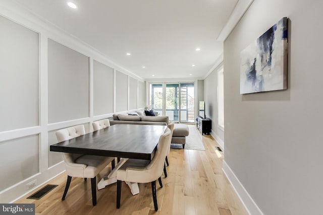 dining room with crown molding and light hardwood / wood-style flooring