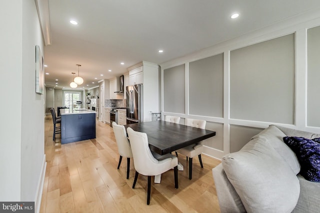 dining space with ornamental molding and light wood-type flooring