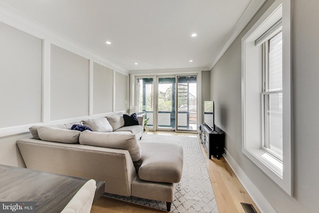 living room with ornamental molding and light hardwood / wood-style floors