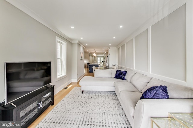 living room with ornamental molding and light wood-type flooring