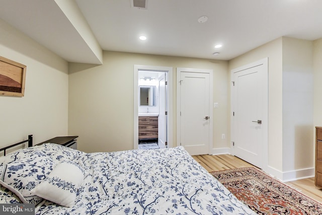 bedroom featuring light wood-type flooring and ensuite bathroom