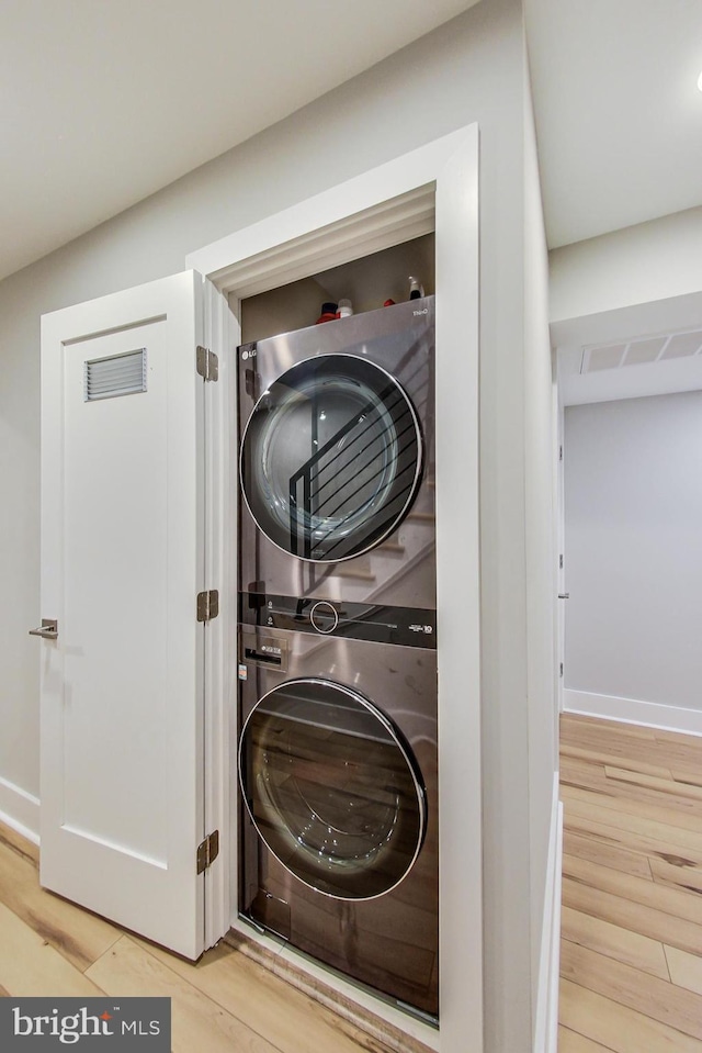 laundry area featuring hardwood / wood-style floors and stacked washing maching and dryer