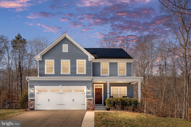 view of front facade with a garage, solar panels, and a porch