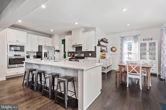 kitchen featuring appliances with stainless steel finishes, white cabinetry, sink, a kitchen bar, and a large island