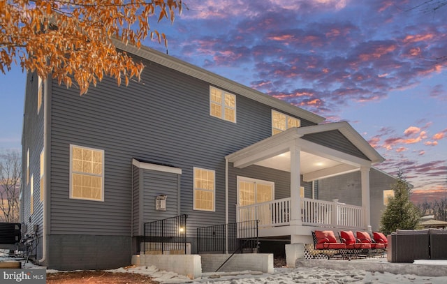 back house at dusk with outdoor lounge area and central AC unit