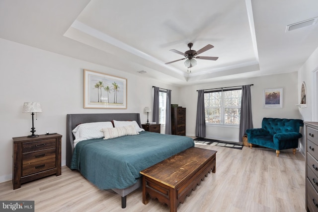 bedroom featuring light hardwood / wood-style floors, a raised ceiling, and ceiling fan